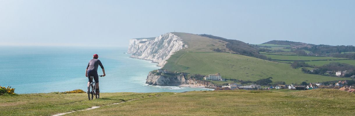 Cyclist riding along the clifftops towards Freshwater Bay, Isle of Wight